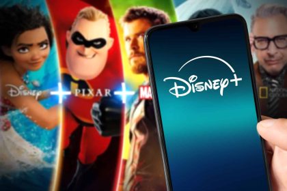 Logo do Disney+ em um smartphone; ao fundo, algumas das atrações oferecidas pelo streaming